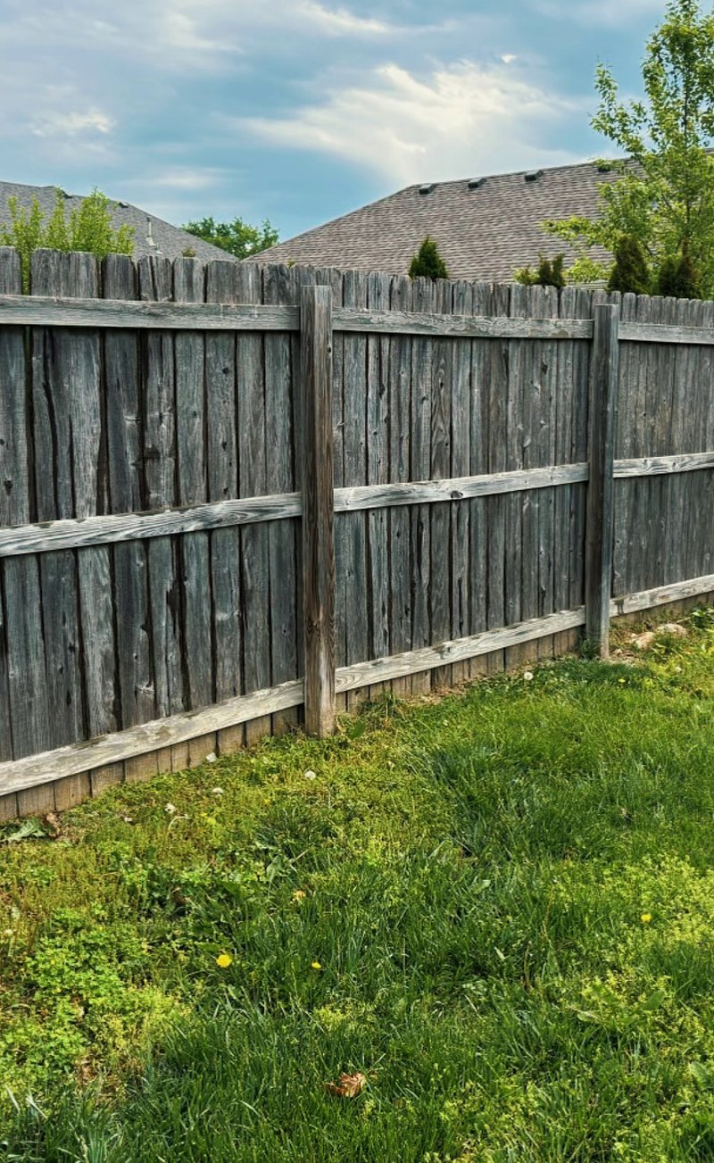 Weathered gray wood privacy fence before cleaning and staining