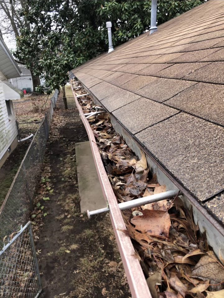Gutter packed with leaves and debris before cleaning